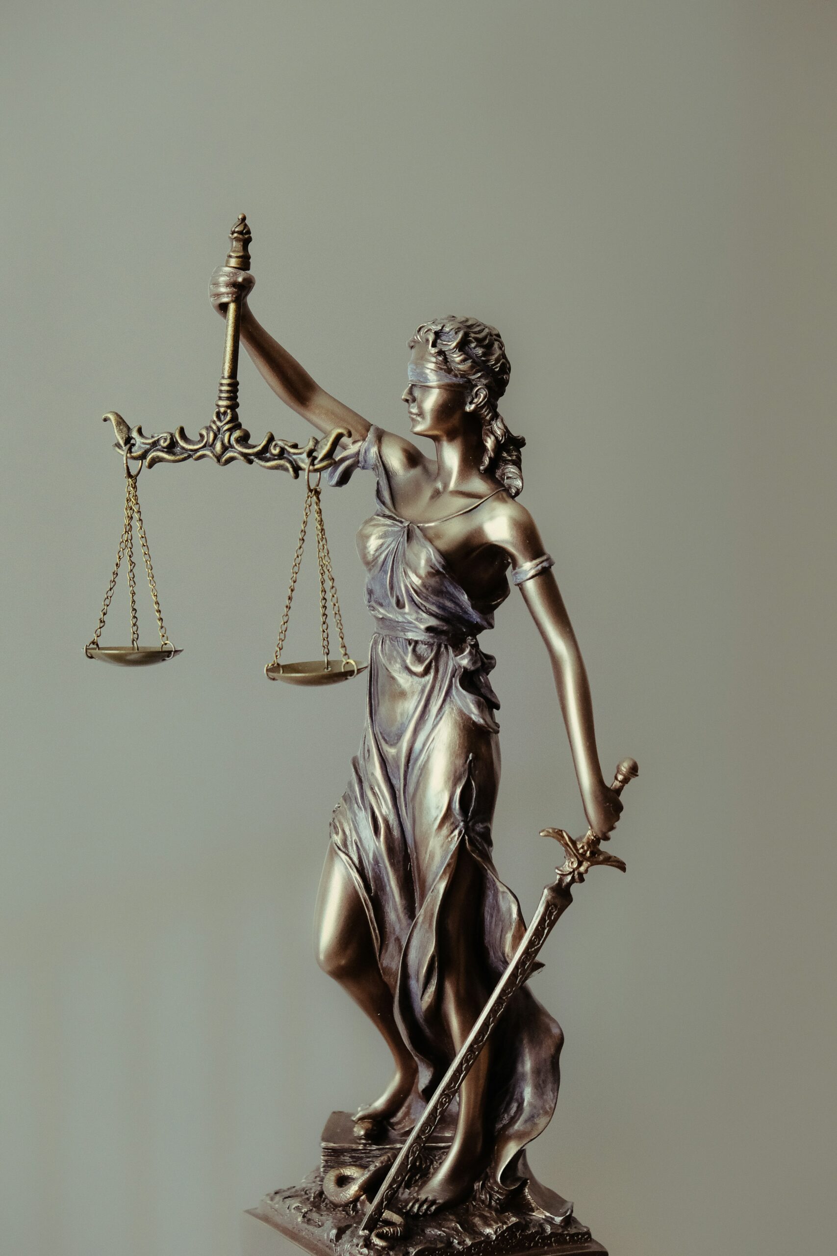 A bronze statue of Lady Justice, holding a scale in one hand and a sword in the other, symbolizing the law and justice.